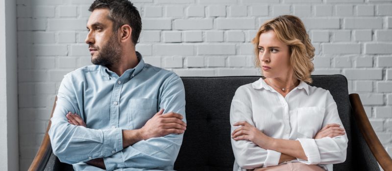 angry couple sitting on couch after quarrel and looking away